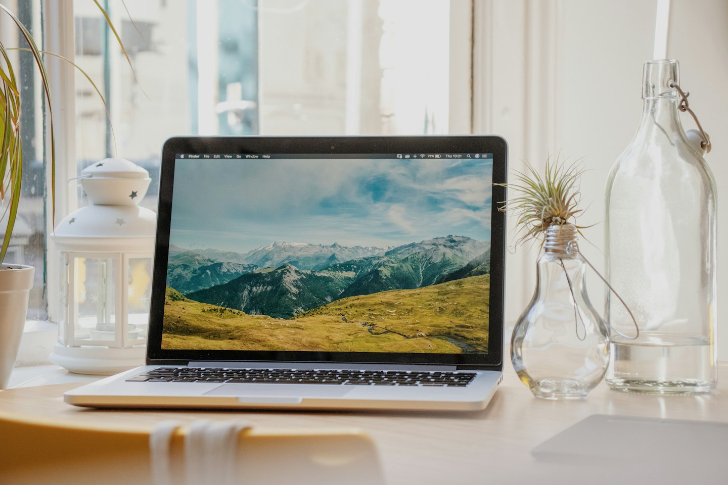 Laptop d'argento con paesaggio montano su una scrivania di legno.